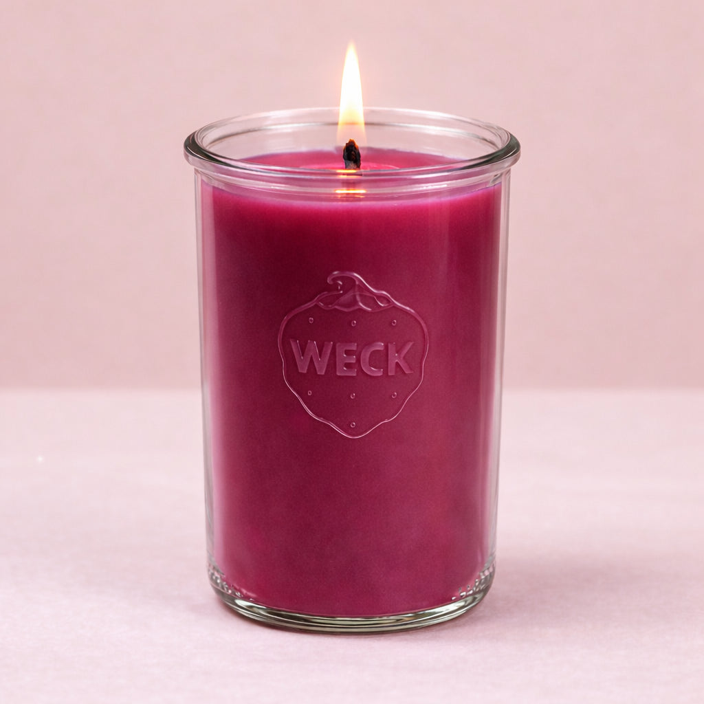 Brennende brombeerrote  CandleDeko XXL Duftkerze im hohen WECK-Sturzglas vor neutralem Hintergrund.