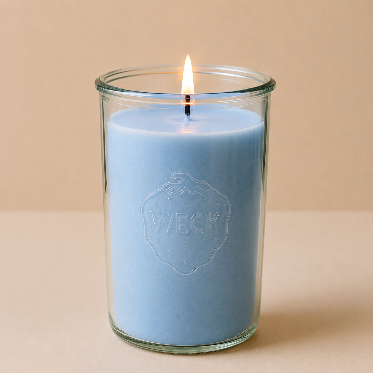 Brennende hellblaue CandleDeko XXL Duftkerze im hohen WECK-Sturzglas vor neutralem Hintergrund