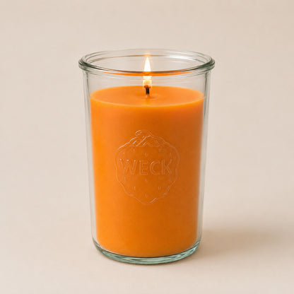 Brennende orange CandleDeko XXL Duftkerze im hohen WECK-Sturzglas vor neutralem Hintergrund.