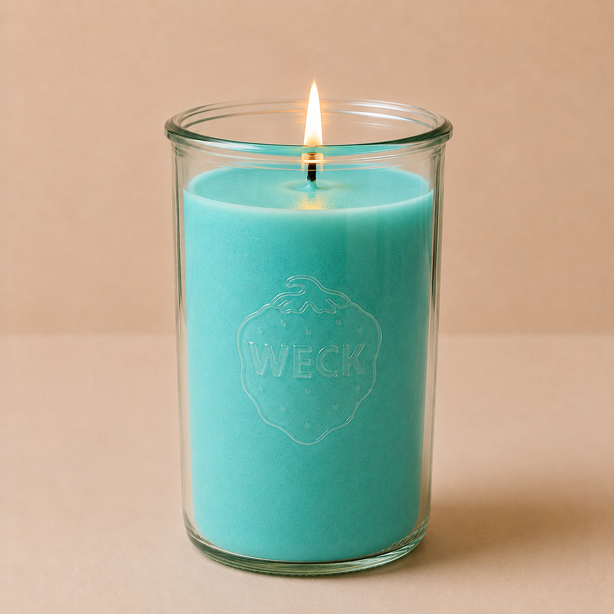 Brennende türkisfarbene CandleDeko XXL Duftkerze im hohen WECK-Sturzglas vor neutralem Hintergrund.