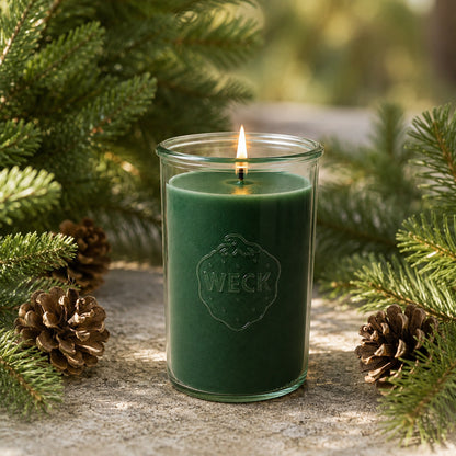 Brennende grüne CandleDeko Tannenbaum XXL Duftkerze im WECK-Sturzglas auf Moosboden im dichten Nadelwald.