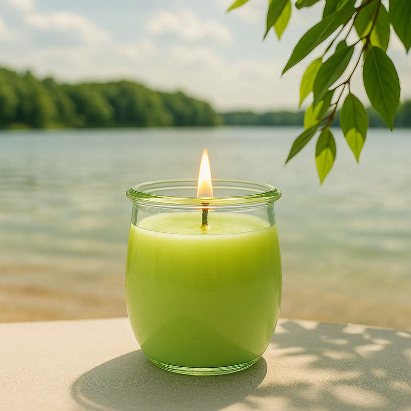 Große Yuzu&Zitrusfrische Duftkerze aus Kokoswachs im WECK-Tulpenglas vor einem See im Sonnenschein.