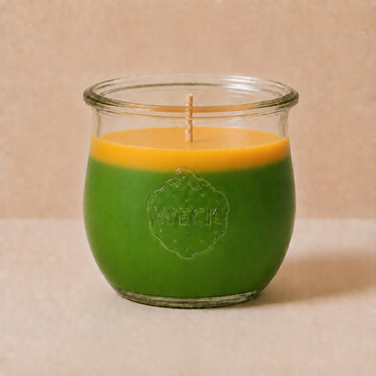 Zweifarbige große Duftkerze aus Kokoswachs im WECK-Tulpenglas von CandleDeko, grün-oranges Wachs vor neutralem Hintergrund.